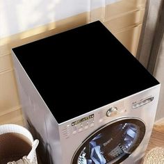 a washing machine sitting on top of a wooden floor next to a basket filled with laundry