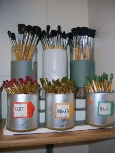 several tin cans with different types of paintbrushes in them