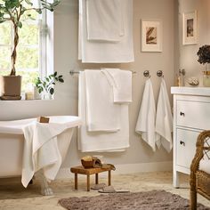 a bathroom with white towels hanging on the wall and a bathtub in the corner