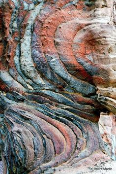 an interesting rock formation with different colors and patterns on it's face, in the desert