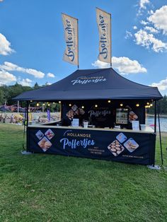 an outdoor food stand on the grass with banners