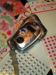 a cell phone sitting on top of a table next to some stickers and paper