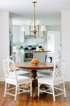 a dining room table with four chairs around it and an island in the back ground