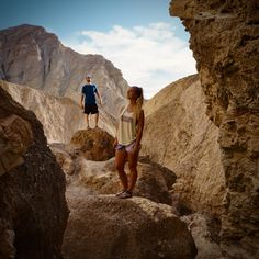 two people standing on rocks in the desert