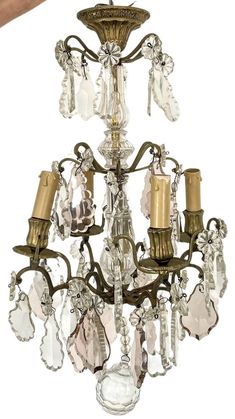 a chandelier with several lights hanging from it's sides and two hands reaching for the light