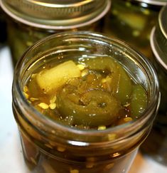 pickles and corn in a jar on a counter top with other jars behind them