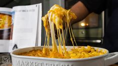 a person is eating macaroni and cheese from a white casserole dish