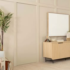 a living room with a plant and a mirror on the wall next to a dresser