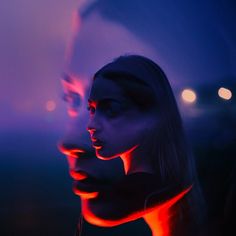 two women with their faces lit up in red and blue light, one is looking at the camera