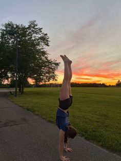 a person doing a handstand in the middle of a road at sunset or dawn