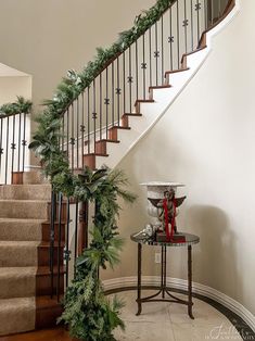 a staircase decorated for christmas with garland and pine cones on the bannister railing