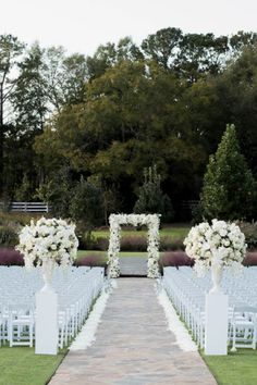 an outdoor ceremony setup with white chairs and flowers