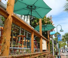 an outdoor cafe with green umbrellas on the outside