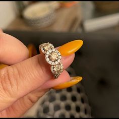 a woman's hand holding an orange manicure with a diamond ring on it