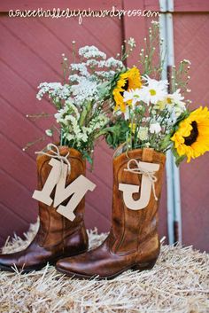 cowboy boots with flowers in them and the letters m are placed on top of hay