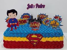 a birthday cake decorated with superman and pop - up characters on it's sides