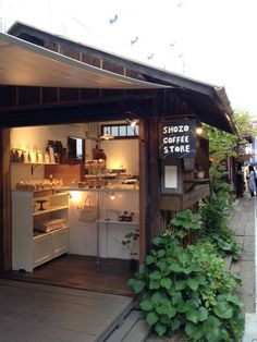 the outside of a small coffee shop with plants