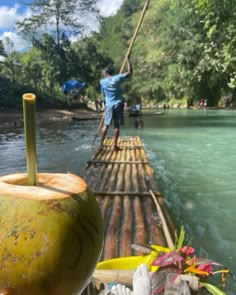 a man is standing on a bamboo raft with an apple