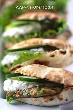 several pita breads are lined up on a white plate with lettuce