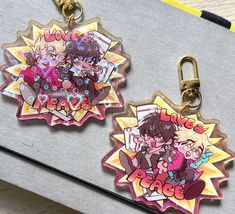 two keychains with anime characters on them sitting on a table next to each other