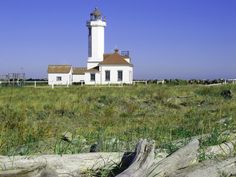 a white lighthouse sitting on top of a lush green field