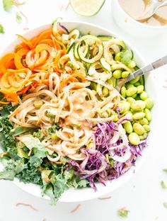 a white bowl filled with vegetables and noodles