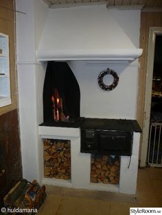 a fireplace with firewood stacked in it and a wreath hanging on the wall next to it