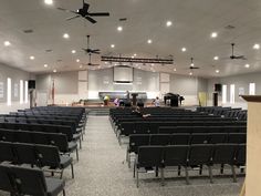 an empty church with rows of chairs in front of the pews and ceiling fans