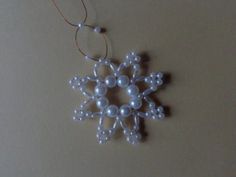 a white snowflake ornament hanging from a string on a table top