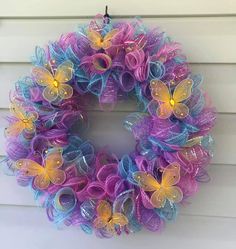 a purple and blue mesh wreath with yellow butterflies on the side of a white house