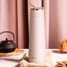 thermos is sitting on a table next to crackers and teapots