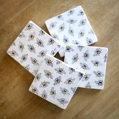 four bees on white paper sitting on top of a wooden table