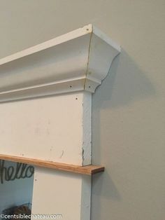 a cat is sitting on top of a shelf in the corner of a room that has been painted white