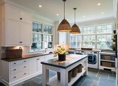 a kitchen with two hanging lights over the sink and an island in front of it