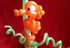 an orange and green balloon sculpture on a red background