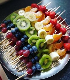 fruit skewers are arranged on a plate with toothpicks and berries in the middle