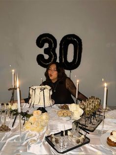 a woman sitting in front of a table with a cake and some candles on it