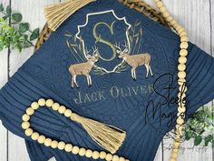 a blue graduation cap with two deer on it and a beaded tassel around the neck