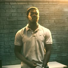 a man standing in front of a brick wall