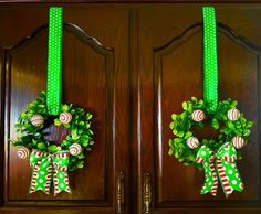 two wreaths with green bows and candy canes hanging on the front door doors