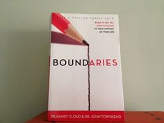 the book boundaries is sitting on top of a wooden table with a pencil sticking out of it