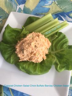 a white plate topped with lettuce and hummus next to celery