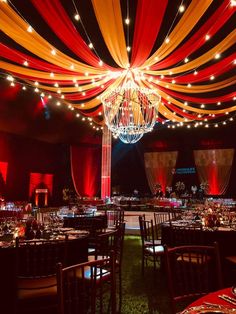 a banquet hall decorated with red, yellow and white draping on the ceiling