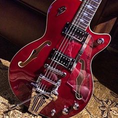 a red electric guitar sitting on top of a carpet