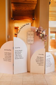 three white signs sitting on top of a tiled floor next to a vase with flowers