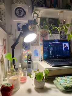 a laptop computer sitting on top of a desk next to a keyboard and plant pots