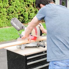 a man using a circular saw to cut wood with a mitt on top of a workbench