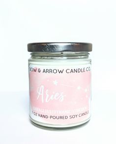 a pink candle is sitting on a white surface with the words aris printed on it