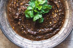 a bowl filled with beans and cilantro on top of a wooden table