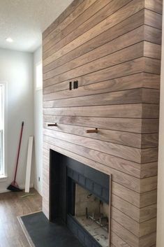 an empty living room with a fireplace and wood paneling on the wall behind it